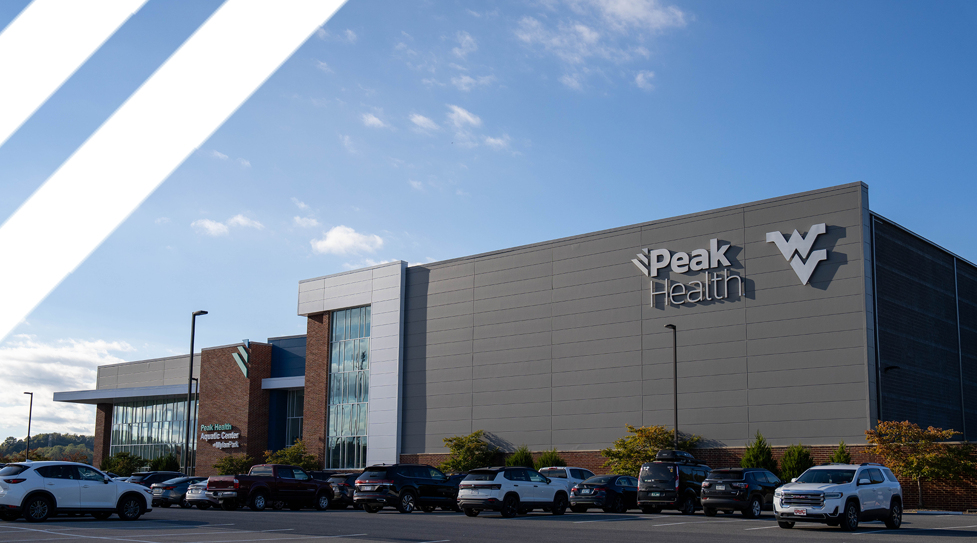 Exterior of Peak Health building with blue sky, parking lot, and cars in foreground; prominent Peak Health sign on the facade.